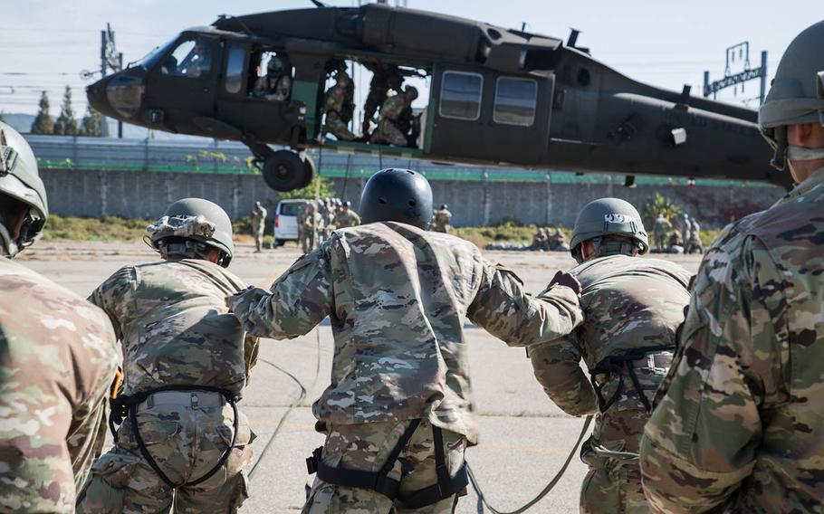 An air-assault instructor keeps two students from being blown away by rotor wash at Camp Mobile, South Korea, Thursday, Oct. 19, 2017.