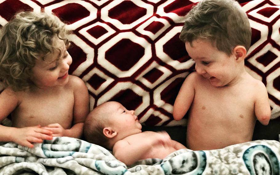 Camden Whiddon, 3, laughs with his siblings at home in Denton, Texas. Camden, whose family has links to the U.S. military in Japan, was born without forearms and legs.