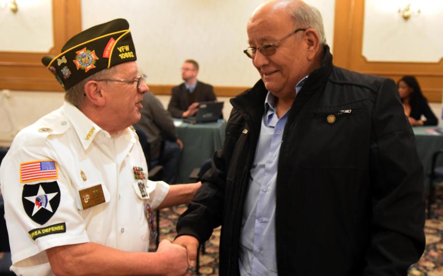 Vietnam War veterans George Quick, left, and Baldemar Guevara shake hands at the retiree appreciation day at Grafenwoehr, Germany, Tuesday, Oct. 24, 2017.