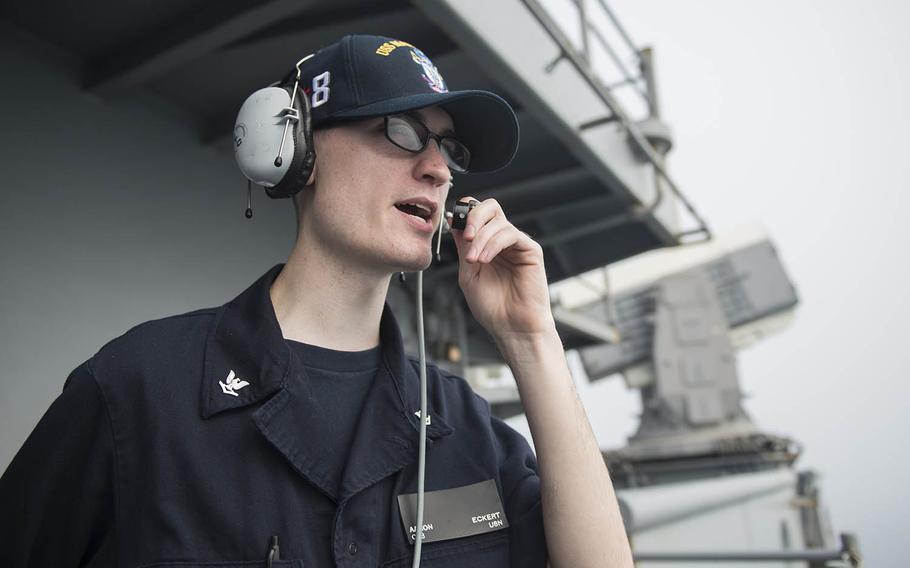A sailor on the USS Makin relays information to bridge watch standers from the fantail as the amphibious assault ship arrives in Hong Kong for a scheduled port visit in April.
