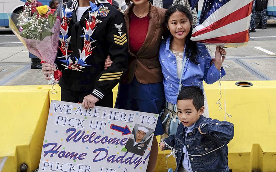 Petty Officer 1st Class Edgar Ibay, a hospital corpsman aboard the USS Ronald Reagan, poses with his family at Yokosuka Naval Base, Japan, Monday, Dec. 4, 2017.