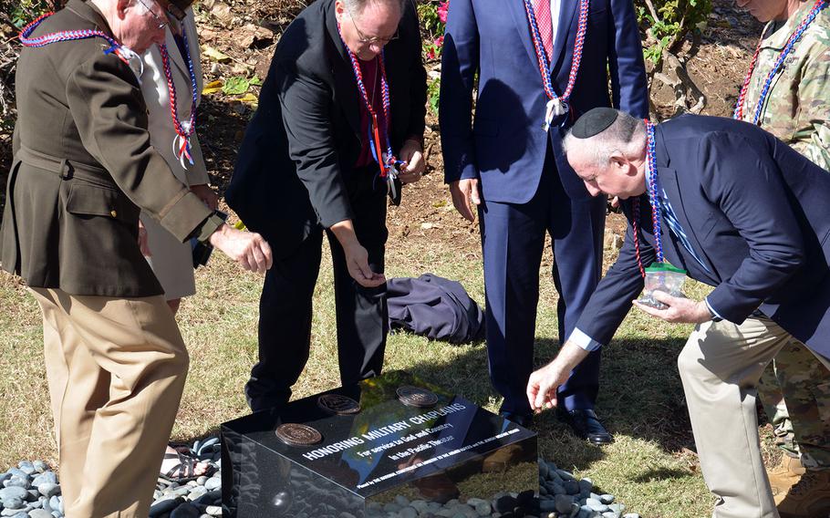 Led by Rabbi Irving Elson, right, current and former military chaplains sprinkle soil from Iwo Jima on a monument for chaplains who served in the Pacific during a dedication ceremony, Wednesday, Dec. 13, 2017, at the National Memorial Cemetery of the Pacific, Honolulu.