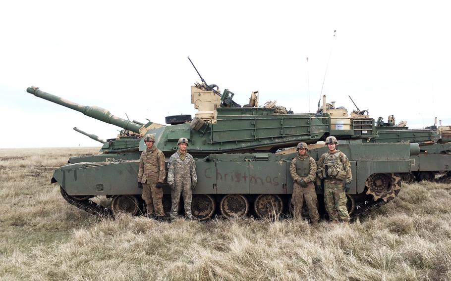 Sgt. James Burton (left), Spc. Brandon Furr, Pvt. Darrenmark Igarta, and 1st Lt. Fedencio Mendez, with Company C of the 2nd Armored Brigade Combat Team, stand by their M1A2 Abrams tank with ''Christmas'' painted in mud on its side, Thursday, Dec. 7, 2017.