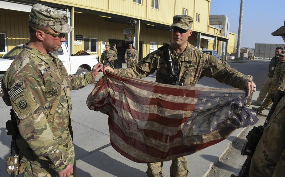 
                Spc. Garrett ''Doc'' Young, pictured here at Bagram Air Field on Wednesday, Dec. 20, 2017, unfurls an American flag scarf his wife gave him for Christmas in 2016. He has carried the scarf in his cargo pocket during his time in Afghanistan, including on the patrol on Nov. 13, 2017, in which a suicide car bomber wounded four of his platoon mates.
                