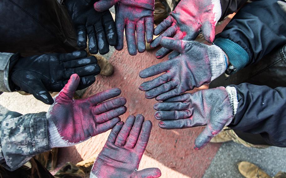 Soldiers from 1st Battalion, 38th Field Artillery Regiment show off their charcoal covered gloves in Yeoncheon, South Korea, Thursday, Dec. 28, 2017.