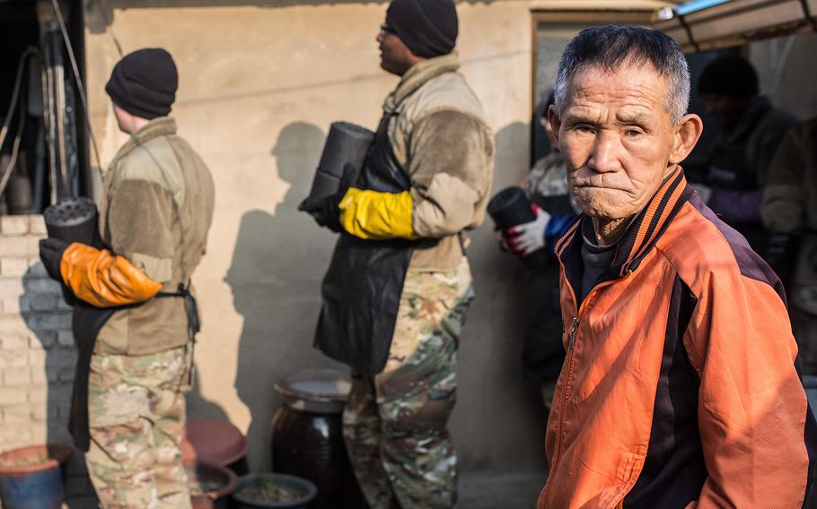 A man watches as soldiers from 1st Battalion, 38th Field Artillery Regiment donate charcoal briquettes to his home in Yeoncheon, South Korea, Thursday, Dec. 28, 2017.