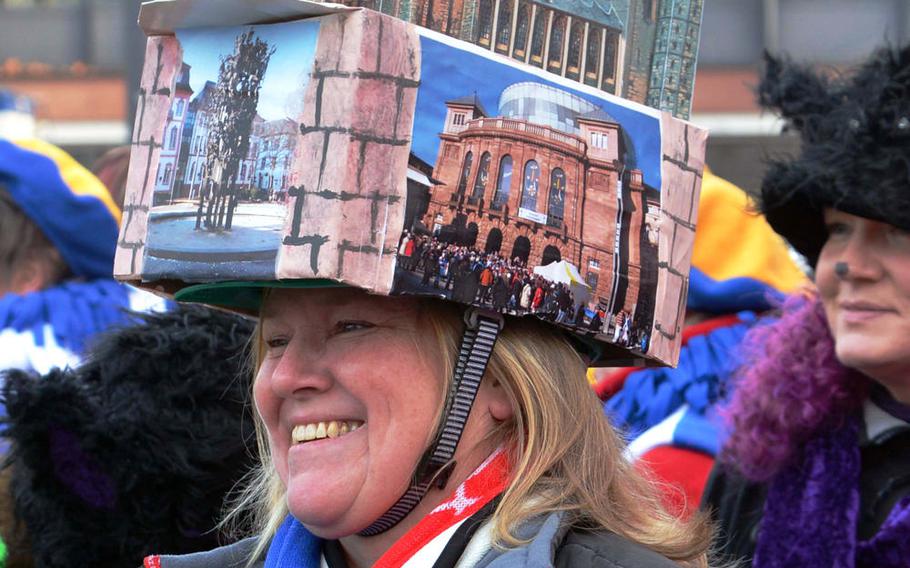 A person celebrating Weiberfastnacht, or women's carnival, in Mainz, Germany, wears a model of the city's famous cathedral on her head. Part of the real thing can be seen in the background in the upper right corner.
