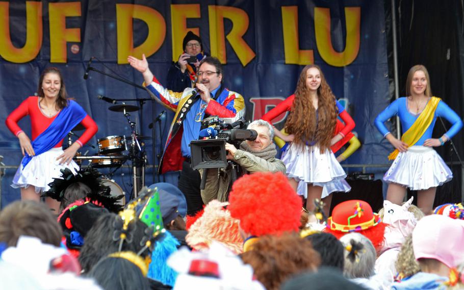 A singer with cheerleaders entertain the crowd during Weiberfastnacht, or women's carnival, on Schillerplatz in Mainz, Germany, Thursday, Feb. 8, 2018. Weiberfastnacht opens the final days of the carnival season in Germany.