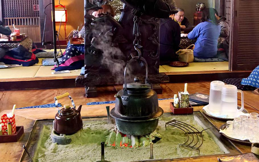 A metal coy fish supports a steaming kettle in the center of a table at Kamado near Marine Corps Air Station Iwakuni, Japan.