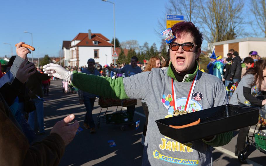 A participant in the carnival parade in Ramstein-Miesenbach, Germany, passes out a sausage to a spectator, Tuesday, Feb. 13, 2018. Besides sausages the spectators were treated to candy, popcorn and more during the parade.