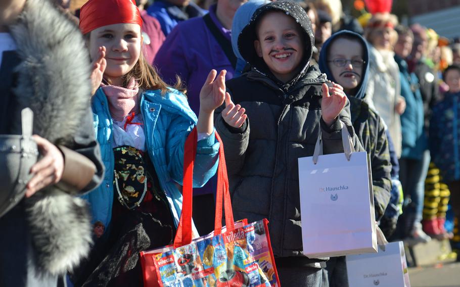 Children clap along to the music as the carnival groups pass by during the 67th annual Ramstein-Miesenbach Fasching parade Tuesday, Feb. 13, 2018. The bags are for the goodies the participants throw to the spectators during the parade.