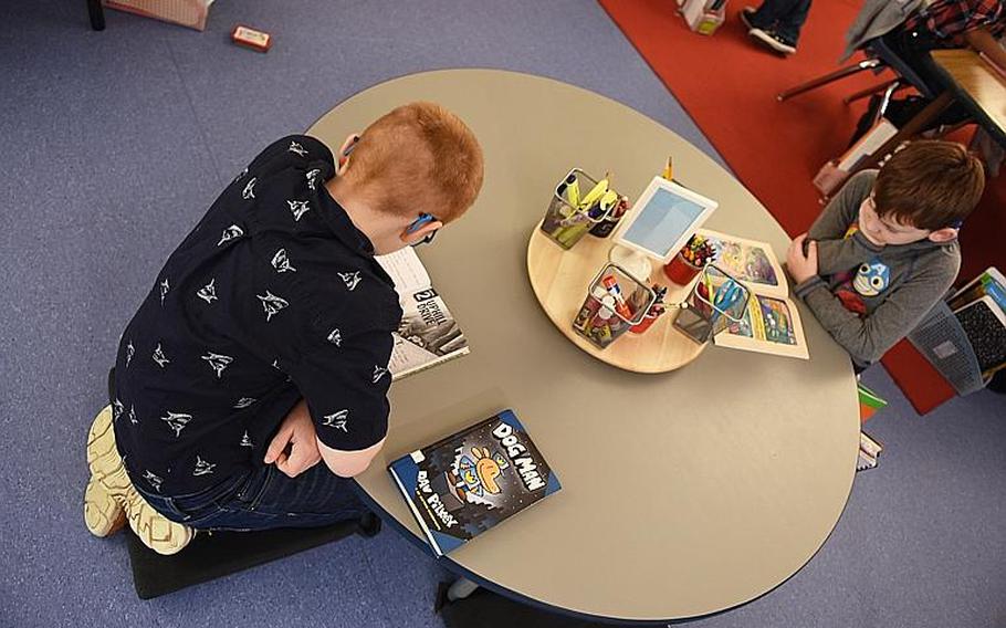 Second-graders Logan Ketchel, left, and Rogan Davis kneel on pillows while reading at Ramstein Elementary School, Germany. Their classroom incorporates a variety of flexible seating, including wobbly stools, pillows and standing while working on computers.