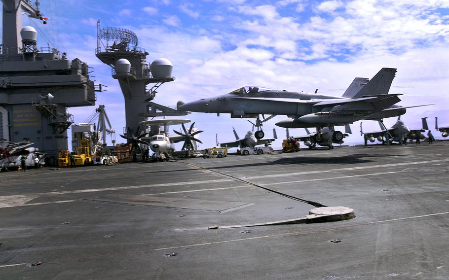 A fighter jet lands aboard the aircraft carrier USS Carl Vinson in the Philippine Sea, Friday, March 16, 2018.