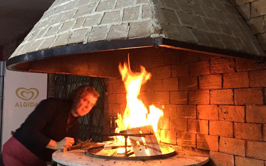 The owner of Ristorante Pizzeria Il Pentolone lights a fire to start the evening. You can choose from a variety of pizza, seafood and meat dishes at his restaurant located inside the Parco Azzurro apartment complex in Pozzuoli, Italy.