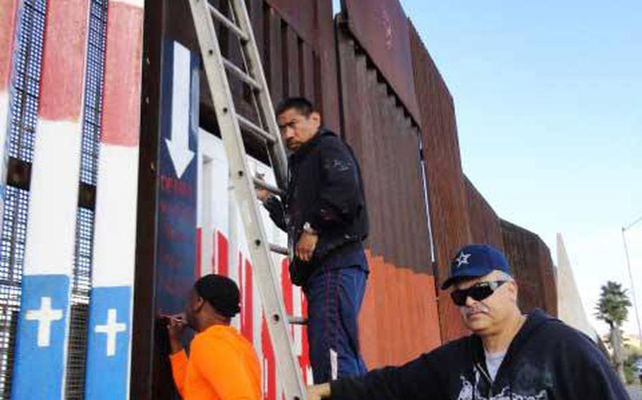 Navy veteran and muralist Amos Gregory works on a mural on the US-Mexico border wall near San Diego, with the help of deported veterans. Gregory finished a mural in 2013 of an upside-down American flag - a distress signal that he says symbolizes the plight of deported veterans.