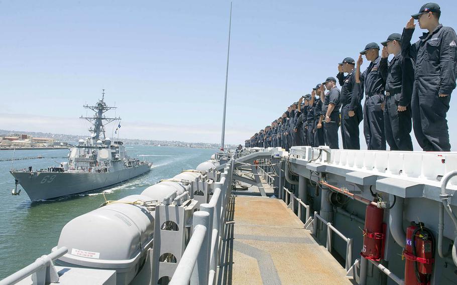 Sailors aboard the USS Essex return salutes to the guided-missile destroyer USS Milius last summer off the coast of Southern California.