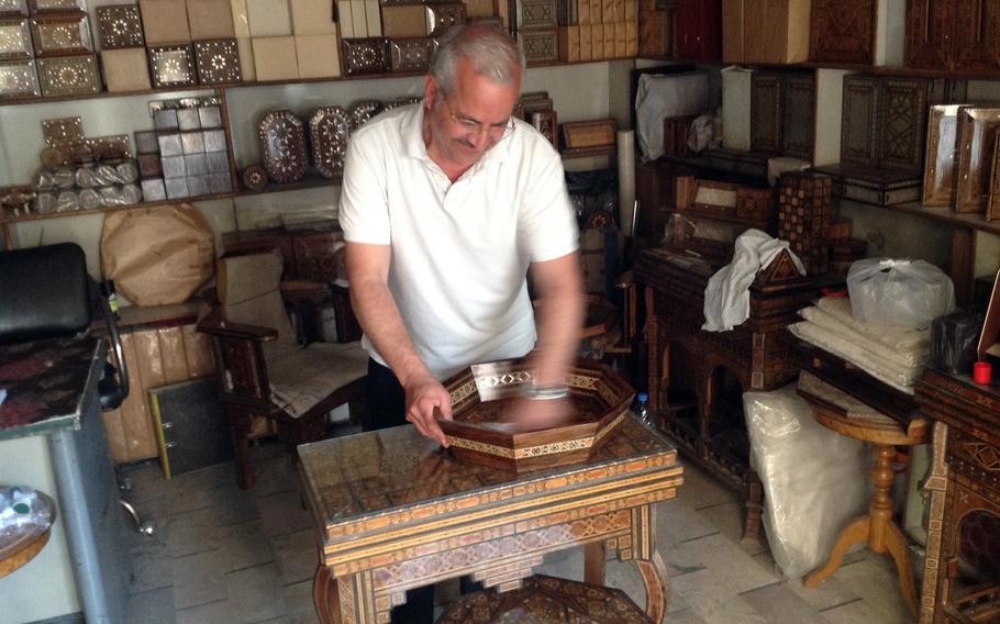 Eli Kassis, owner of a shop making the famous Syrian furniture with inlaid mother-of-pearl mosaics, works on a tray for export. Kassis said business has improved and life has become more normal since Islamist rebels have been expelled.