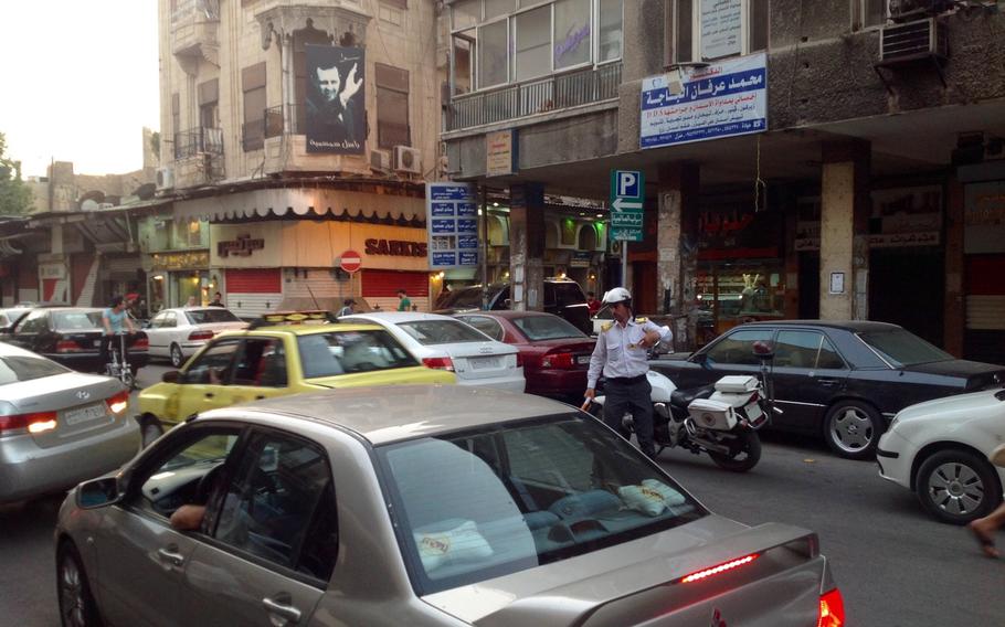 A police officer appears to be overwhelmed by the city's notoriously unruly drivers. Police officers have again started issuing speeding and parking tickets for the first time since the war started in 2011. The change reflects a sense of normality that has returned to the capital.