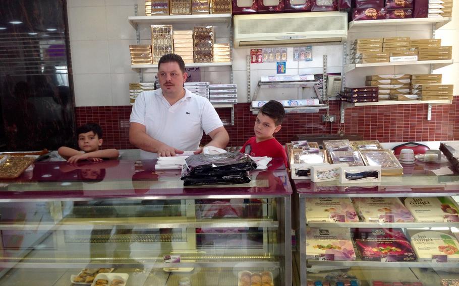 Mohammad el-Zayed, manager of Nabeel's Sweets in Damascus, Syria, and his two sons prepare boxes of candy in the shop. The company plans to hire new workers to cater to increased demand after the end of rebel shelling in April.