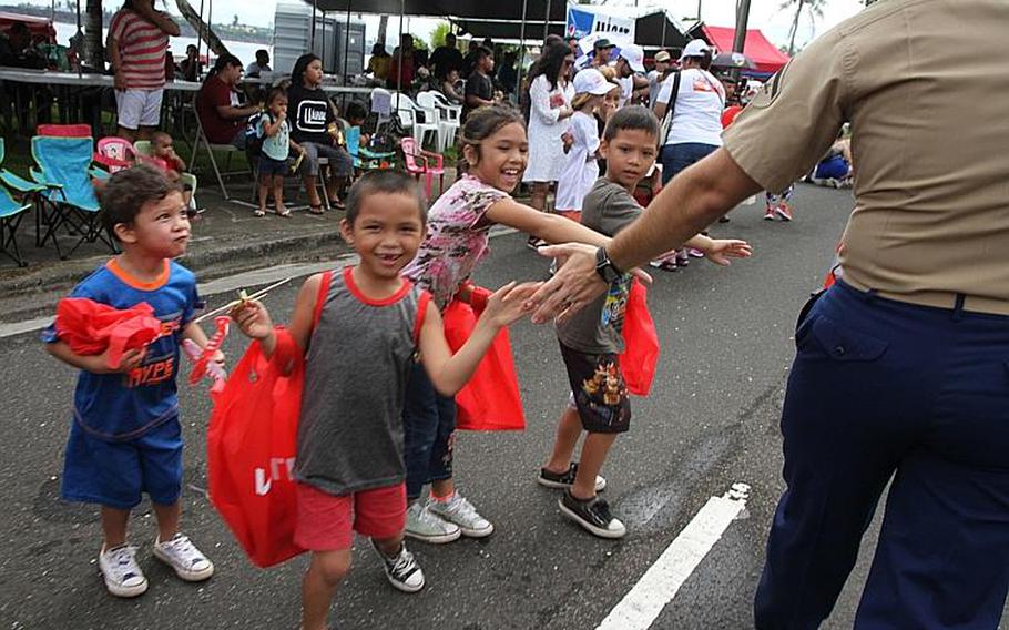 Marine Sgt. Victor Iannelli of the III Marine Expeditionary Force Band greets children along the parade route during Guam's annual Liberation Day festivities, Saturday, July 21, 2018.