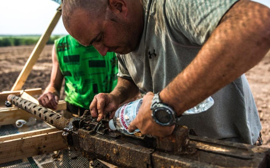 Air Force Sr. Master Sgt. Jeremy Raymond with the Defense POW/MIA Accounting Agency cleans a .50-caliber machine gun on July 28, 2016. The gun was mounted to an aircraft during World War II and found during a DPAA recovery operation in Novi Troy Any, Ukraine.