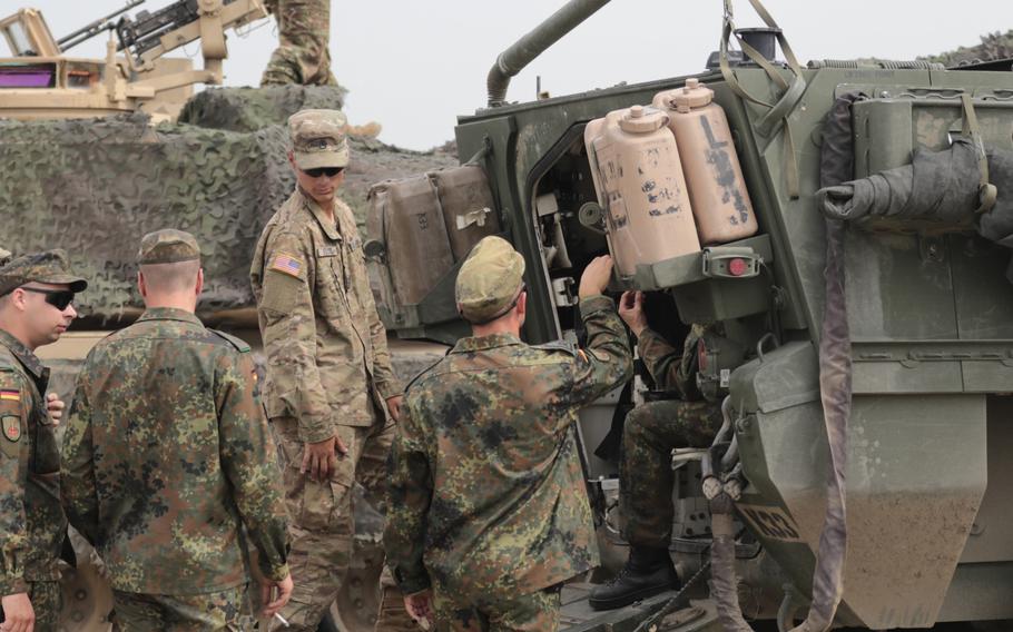 Staff Sgt. Keenan M. Kozak, a tank commander, listens to questions from German soldiers about the Stryker vehicle prior to the opening ceremonies of Noble Partner 18 at the Vaziani Training Area, Georgia on Aug 1, 2018.