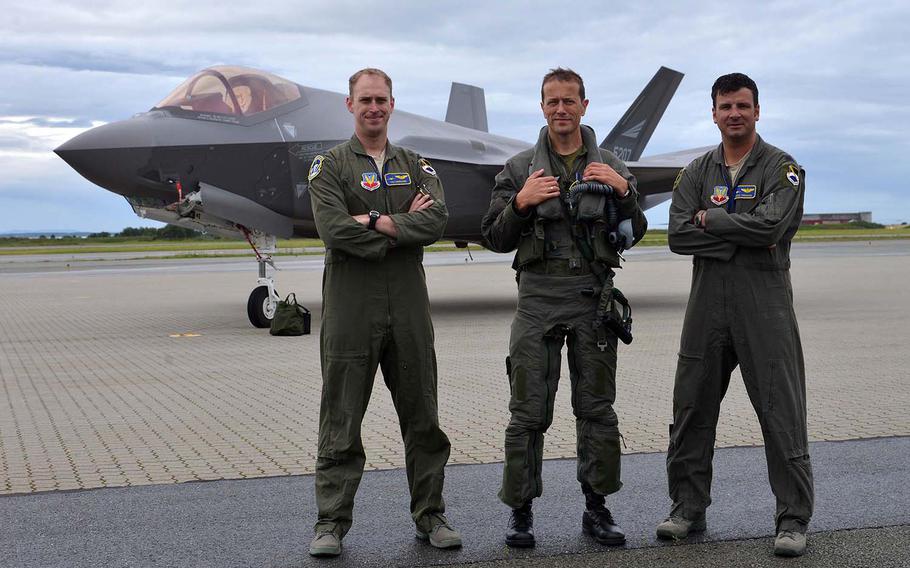 F-22 Raptor pilots Capt. Ian Gregoire, left, and Lt. Col. Matthew Tromans flank Norwegian F-35 pilot Maj. Morten Hanche as they pose for photographers after landing their fifth-generation aircraft at Orland Main Air Station, Norway, Wednesday, August 15, 2018.