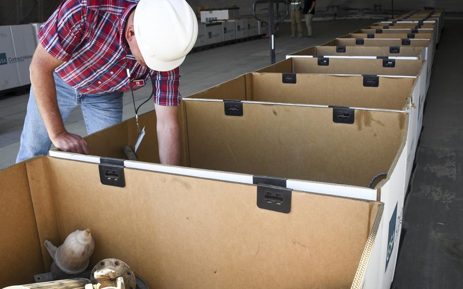 Mark McRae, a Defense Department civilian, digs through boxes of discarded material such as ammo cans, fire extinguishers, and rubber tubing at a scrapyard at Bagram Air Field, Afghanistan, Oct. 25, 2018.