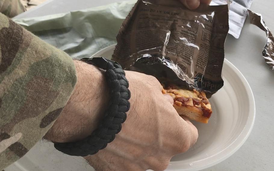 A U.S. servicemember pulls a Meal, Ready to Eat pepperoni pizza from its bag during a taste test of the new military ration at NATO headquarters in Kabul, Afghanistan, on Wednesday, July 4, 2018.
