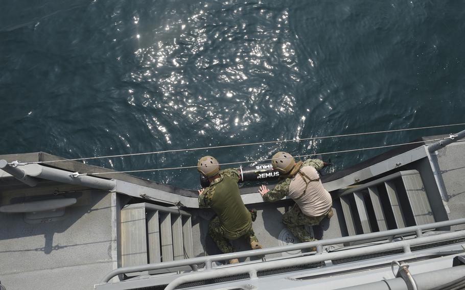 Two sailors launch a mine-hunting sonar device during Mine Countermeasures Exercise 18-3 in the Persian Gulf, Tuesday, Sept. 11, 2018.