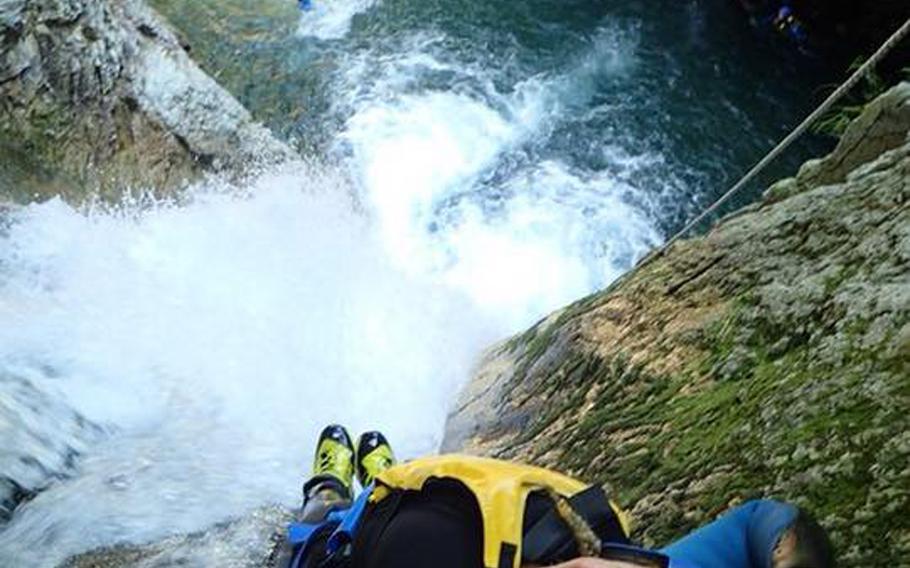 Stars and Stripes reporter Caitlin Doornbos rappels down a 20-meter waterfall before dropping into the water on a Canyons tour. Canyoning encompasses many forms of traveling through canyons, including climbing, swimming, rappelling and jumping. (Courtesy of Canyons)