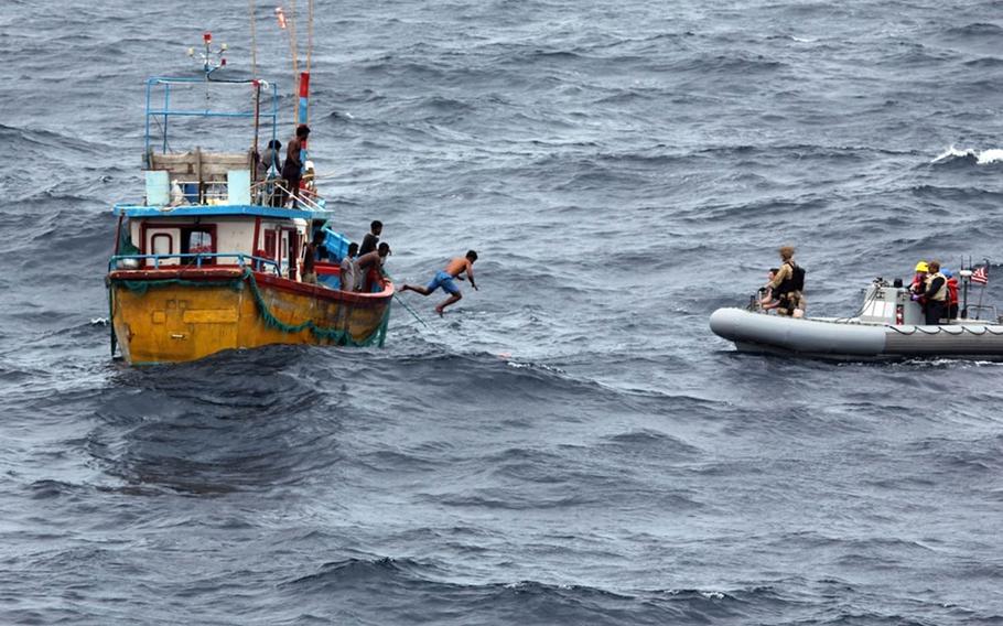 A Sri Lankan fisherman jumps to swim to an inflatable boat from the guided-missile destroyer USS Decatur in the Indian Ocean, Sunday, Oct. 7, 2018.