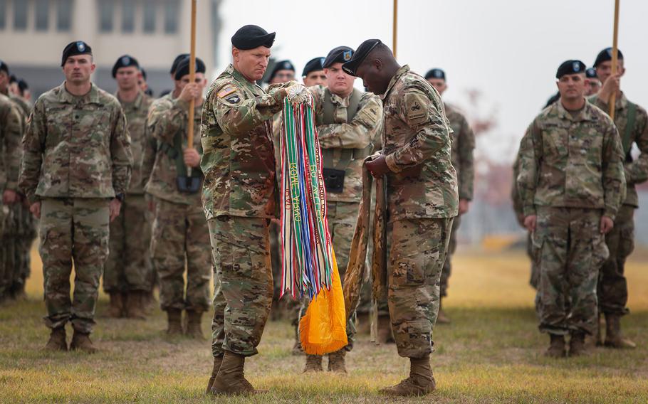 Col. Marc Cloutier and Command Sgt. Maj. Michael Oliver of the 3rd Armored Brigade Combat Team, 1st Armored Division, unfurl their units colors during a transfer of authority ceremony at Camp Humphreys, South Korea, Monday, Oct. 22, 2018.