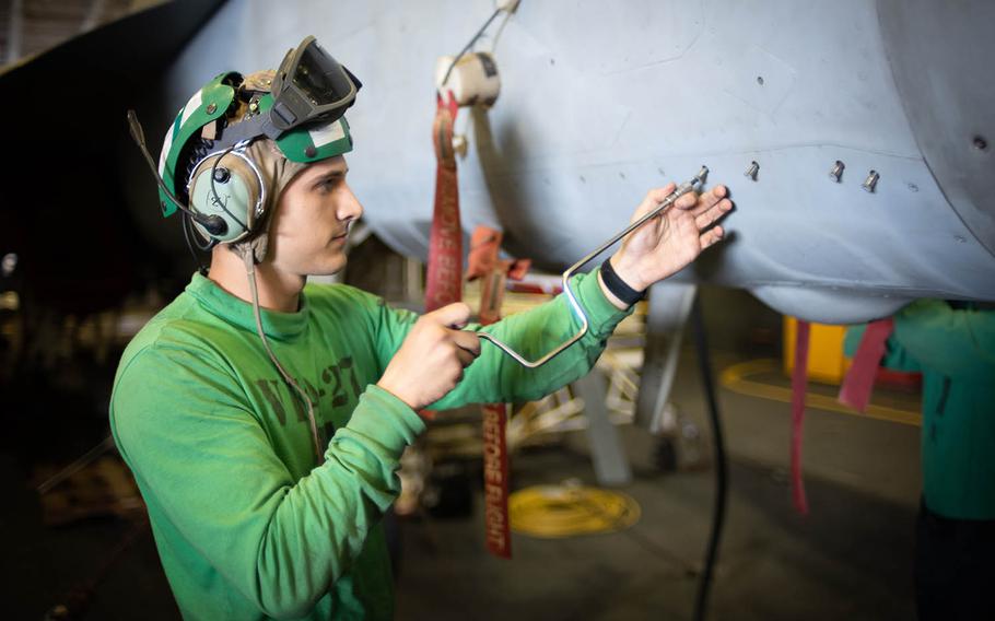 A mechanic works on an F-18 Super Hornet aboard the aircraft carrier USS Ronald Reagan at sea during Keen Sword drills, Saturday, Nov. 3, 2018.