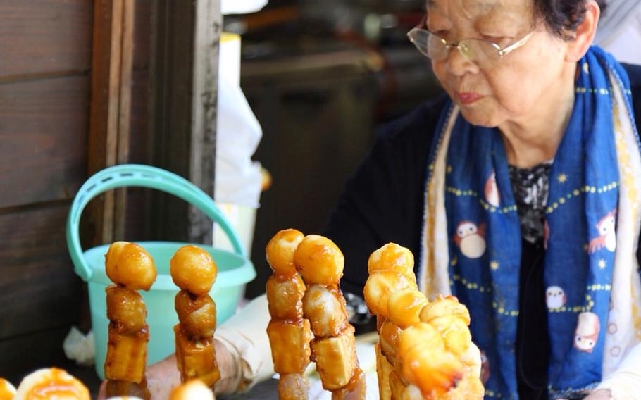 A food stand employee tends to the sweet miso-grazed dekomawashi roasting on the grill near Iya-no-Kazurabashi.