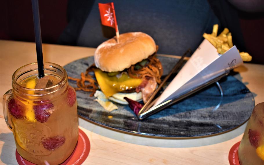 A bacon cheeseburger known as the Joseph is presented along with a side of fries and an Orange Berry detox water at Franz und Sissi restaurant in Kaiserslautern, Germany. The restaurant offers a lunch special adding fries and a specialty drink for 3.95 euros above a burger's menu price.