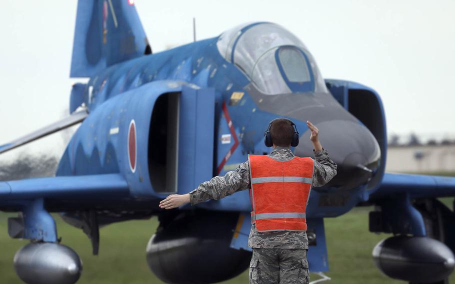 A U.S. airman guides a Japan Air Self-Defense Force RF-4E Phantom assigned to the 501st Tactical Reconnaissance Squadron at Yokota Air Base, Japan, Sept. 16, 2016.