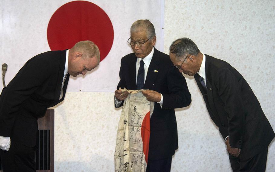 Senior Master Sgt. Lowell Armstrong returns a World War II-era flag to family members of its original owner during a ceremony in Takasaki, Japan, Thursday, Feb. 14, 2019.