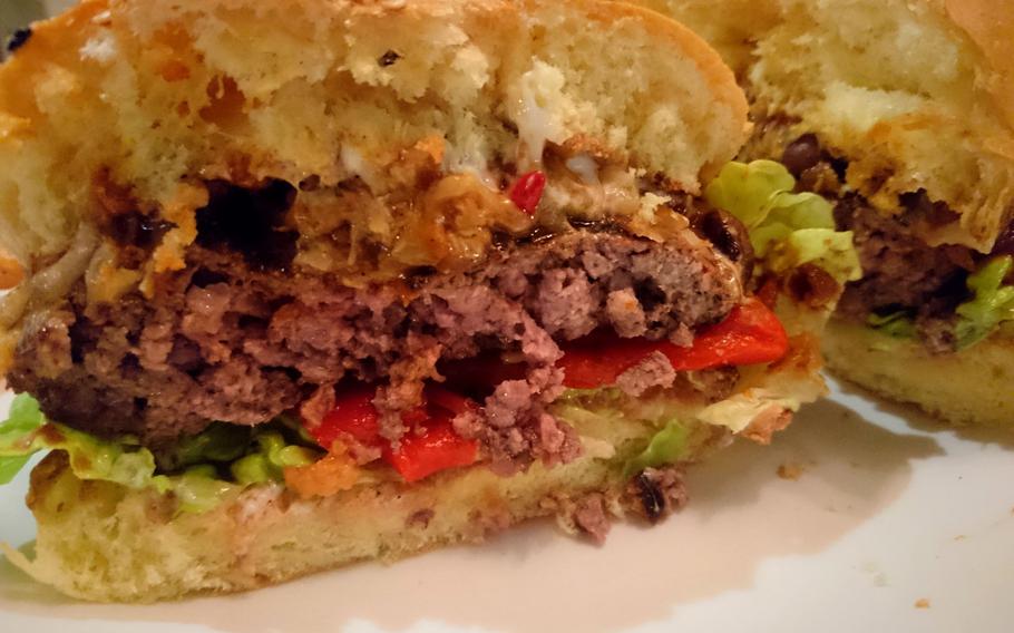 A bisected order of the weekly burger creation at Bill's Restaurant in Bury St Edmunds, England, Feb. 26. The black bean chili burger had melted white cheese slathered over grilled chopped onions, a thick beef patty, lettuce and mildly spicy red peppers.