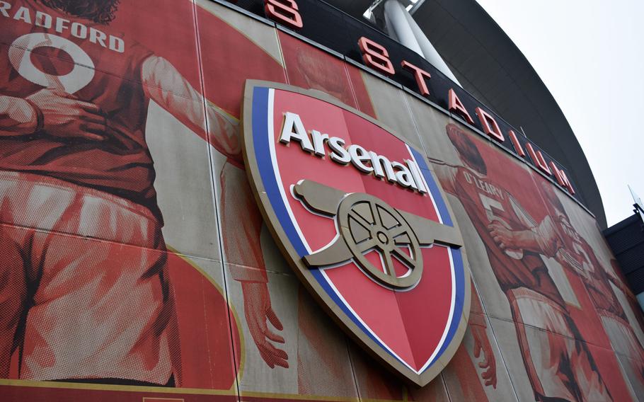 The logo of the Arsenal soccer team and a mural of legendary Arsenal players adorn the outside of Emirates Stadium in London. The team's "Arsenalization" project increased the amount of historic Arsenal imagery on the new, modern stadium.