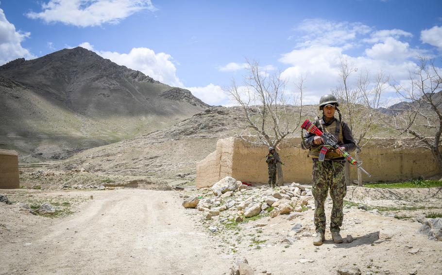 Afghan soldiers guard a temporary checkpoint in Logar province on May 2, 2019. Taliban fighters often descend from these mountains (background) while moving around the province.