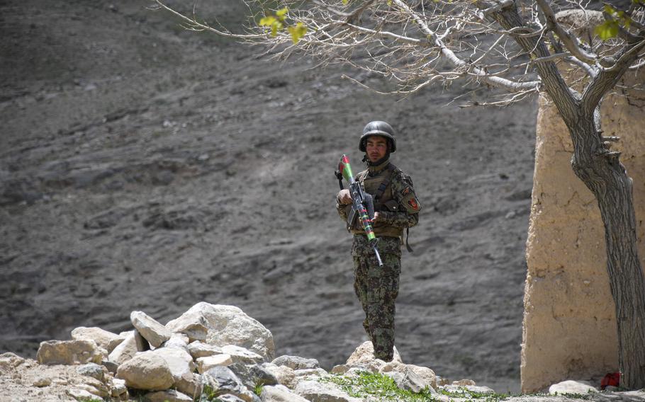 An Afghan soldier guards a temporary checkpoint in Logar province on May 2, 2019. Taliban fighters often descend from these mountains (background) while moving around the province.