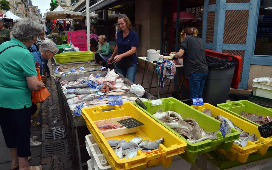Shoppers stop to inspect the fish on sale at a stand at the Wednesday morning market on Rue Saint Jean in Bayeux, France.