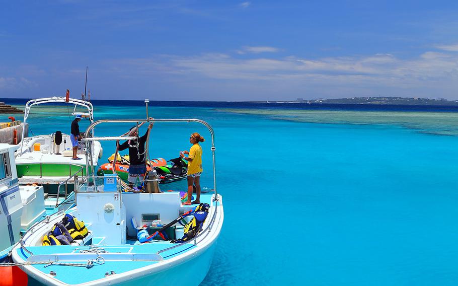 Snorkeling-tour staffers chat on their boat in Minnajima, Okinawa.