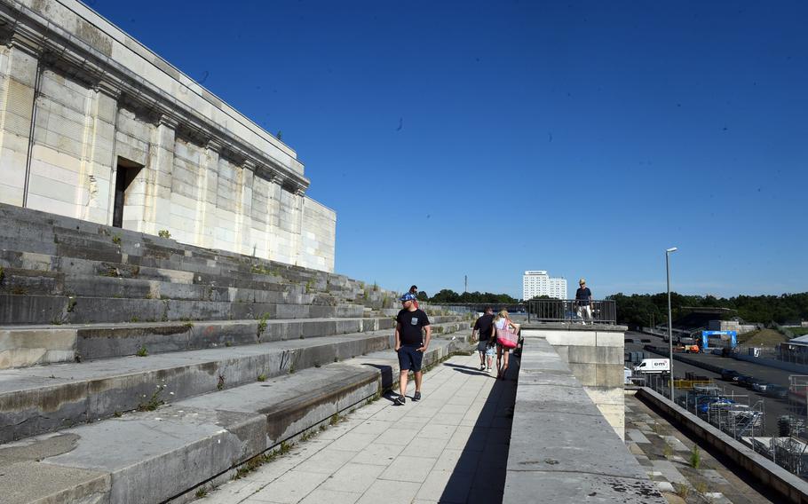 Tourists walk around the viewing stands of the Nazi Party Rally Grounds in Nuremberg, Germany. One tourist stands in Hitler's area near the ledge.
