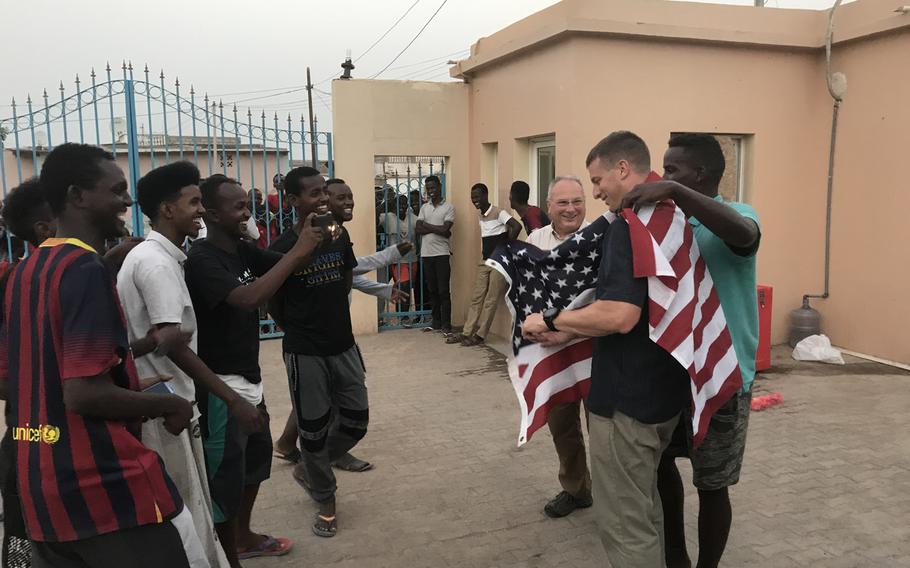 Djiboutian Doudou Roblah drapes a flag over U.S. Army Capt. Noah Hodges' shoulders as Capt. Mike Volk and Roblah's friends look on outside a vocational school in the capital of Djibouti on Thursday, June 13, 2019. U.S. Embassy officials say an English language discussion group the soldiers lead at the school helps to support diplomatic and development efforts in Africa.
