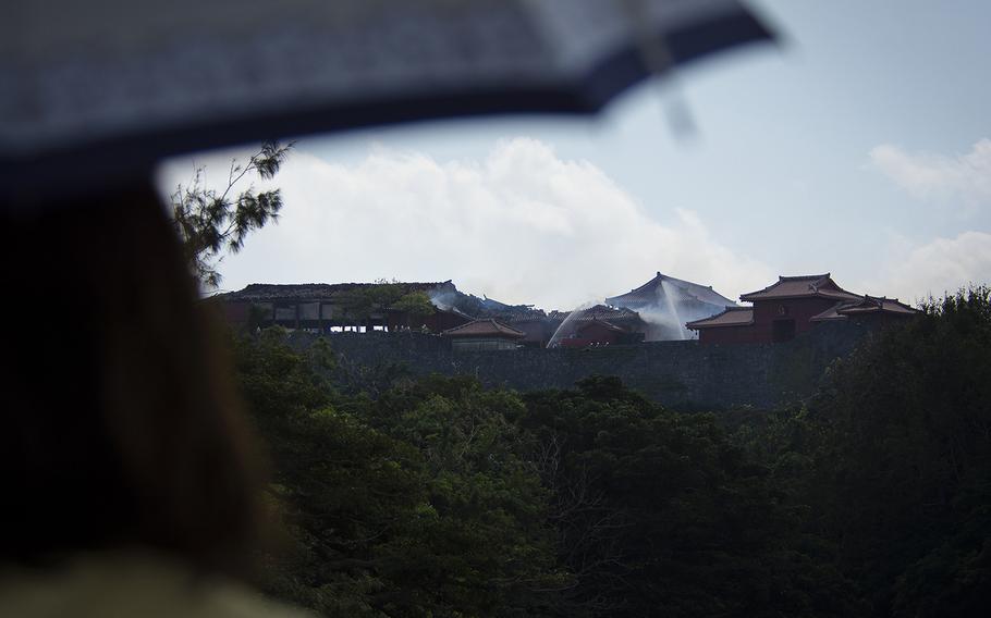 People watch as firefighters work to extinguish a blaze at Shuri Castle in Naha, Okinawa, Thursday, Oct. 31, 2019.