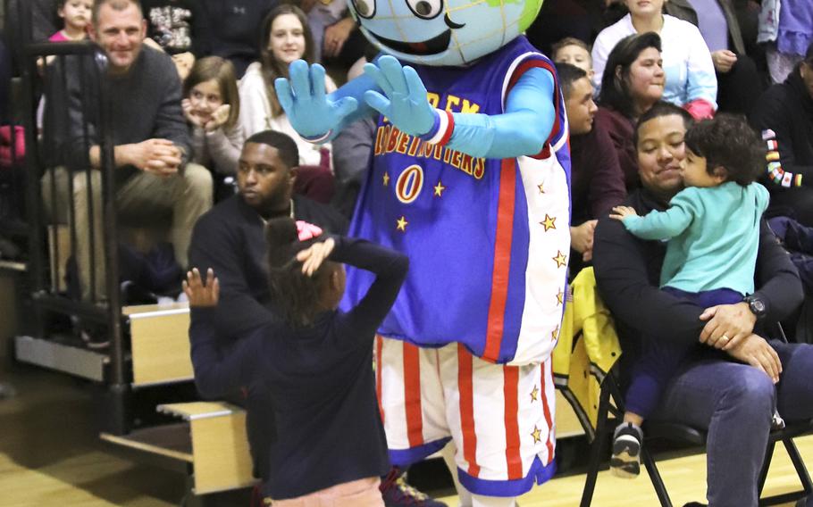 Harlem Globetrotters mascot Globie interacts with a fan during a game at the Dragon Fitness Center, Aviano Air Base, Italy, Nov. 12, 2019.