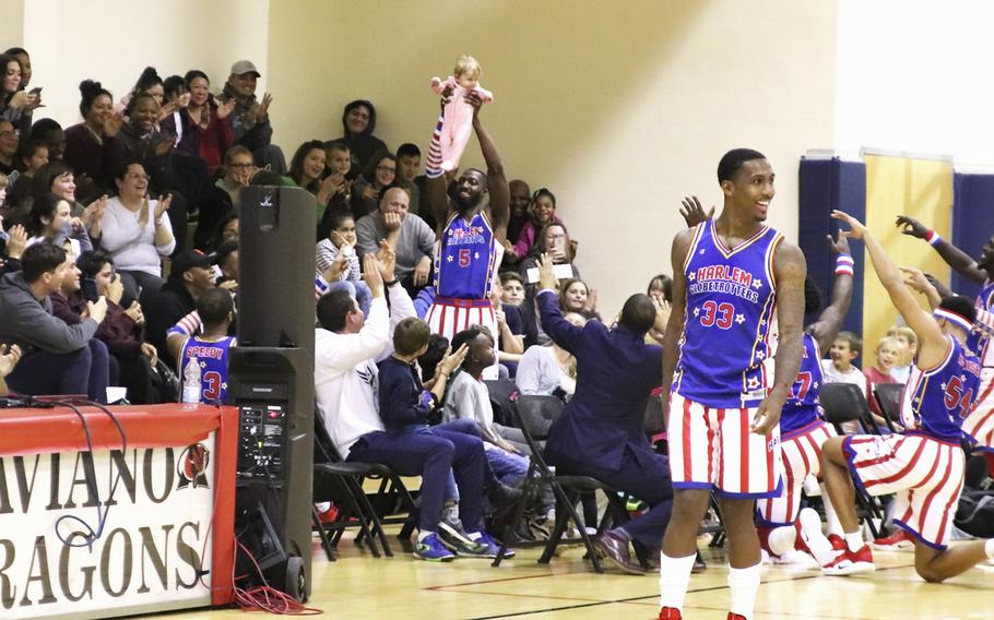 Harlem Globetrotter Bulldog Mack lifts a baby in the crowd as the "Lion King" theme song plays during a game at the Dragon Fitness Center, Aviano Air Base, Italy, Nov. 12, 2019.