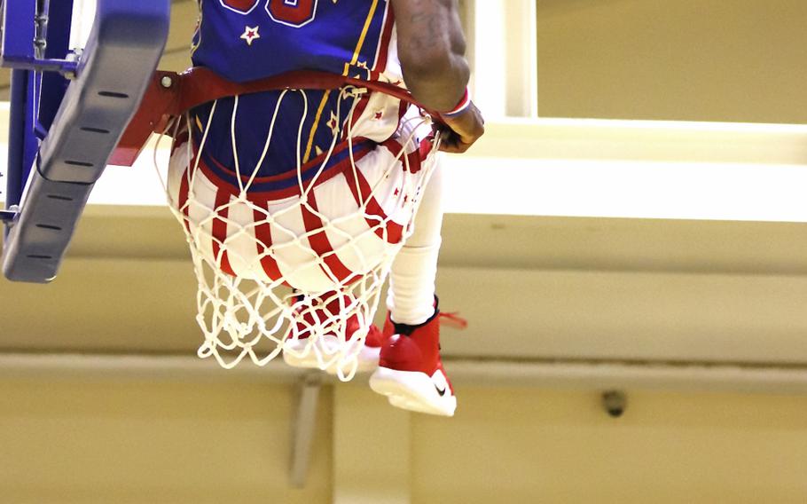 Harlem Globetrotter Bulldog Mack sits inside a basketball hoop during a game at the Dragon Fitness Center, Aviano Air Base, Italy, Nov. 12, 2019.